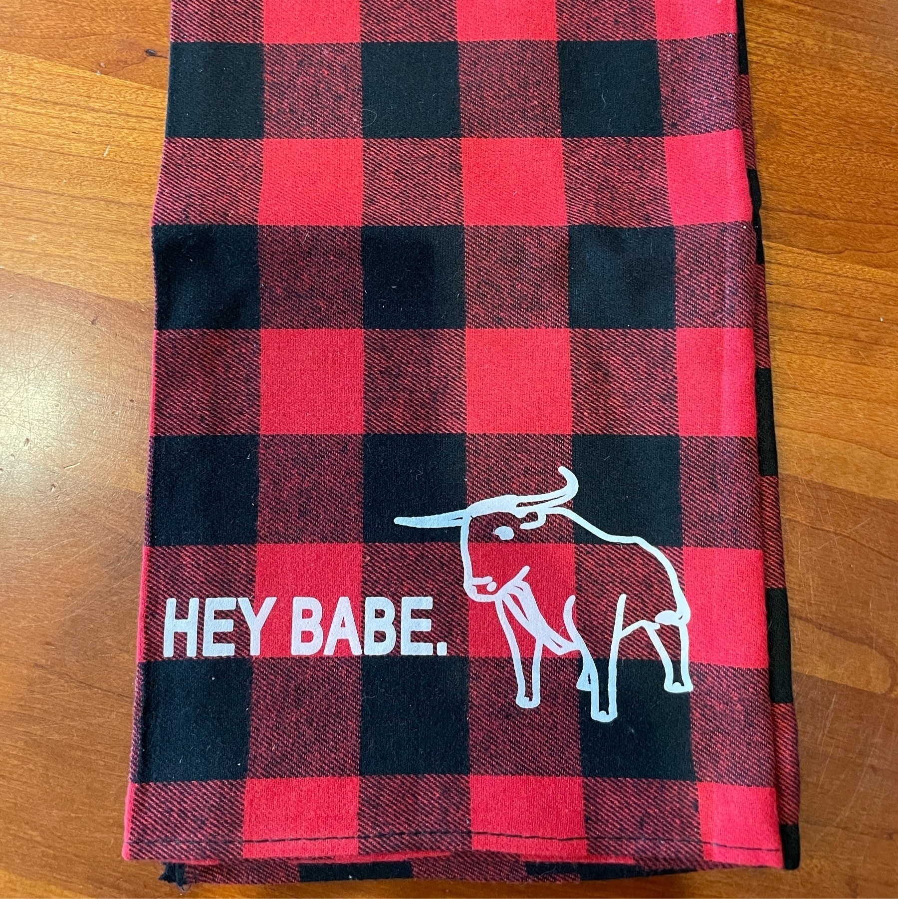 Red-and-black plaid dish towel with text of "Hey Babe" and graphic of Babe the Blue Ox