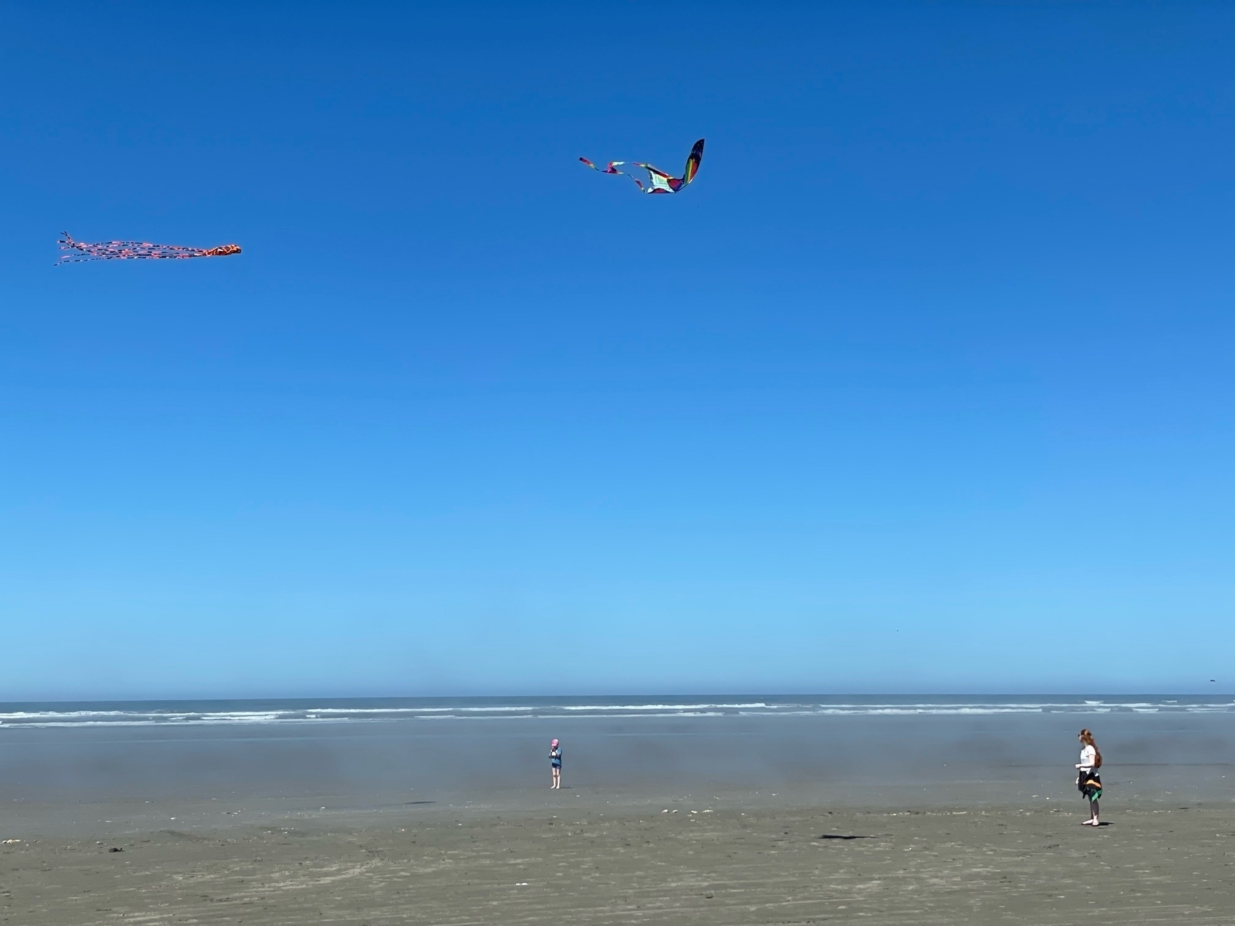 Two girls flying kites on the beach