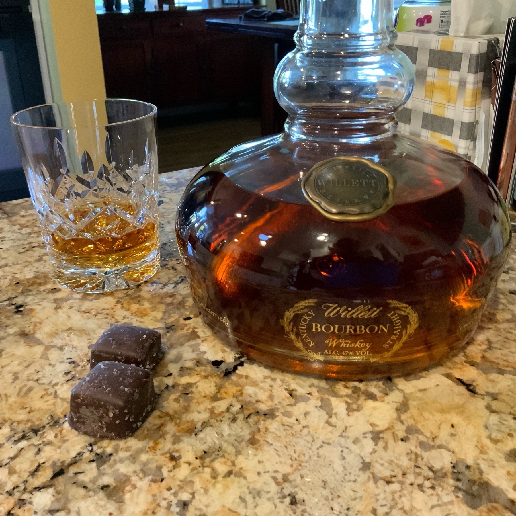 glass of Willett bourbon and two dark chocolate caramels